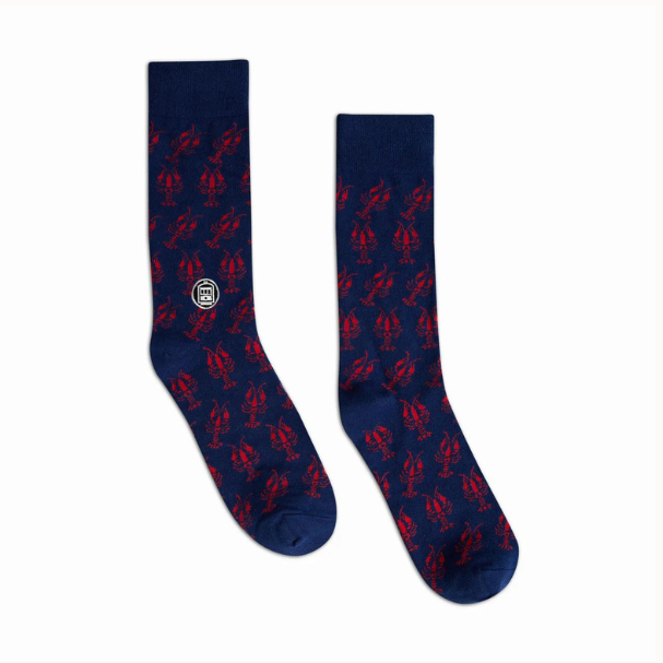 Textile socks by Streetcar Socks featuring a pair of navy blue socks with a repeating pattern of bright red crawfish and a white St. Charles Streetcar icon representing New Orleans