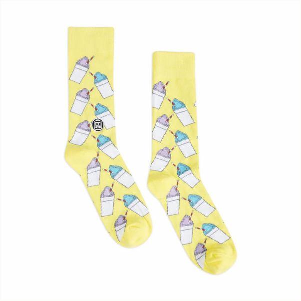 Cotton blend crew socks by Bonfolk featuring a repeating pattern of purple and blue New Orleans snoballs with red-striped straws and a small circular St. Charles streetcar logo on a bright yellow base against a white background