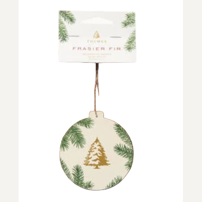Scented paper ornament by Thymes featuring an iconic gold-foil Frasier Fir tree and green pine branch details hanging from a brown cord against a neutral white background